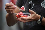 A fan eats a fresh bowl of strawberries and cream.
